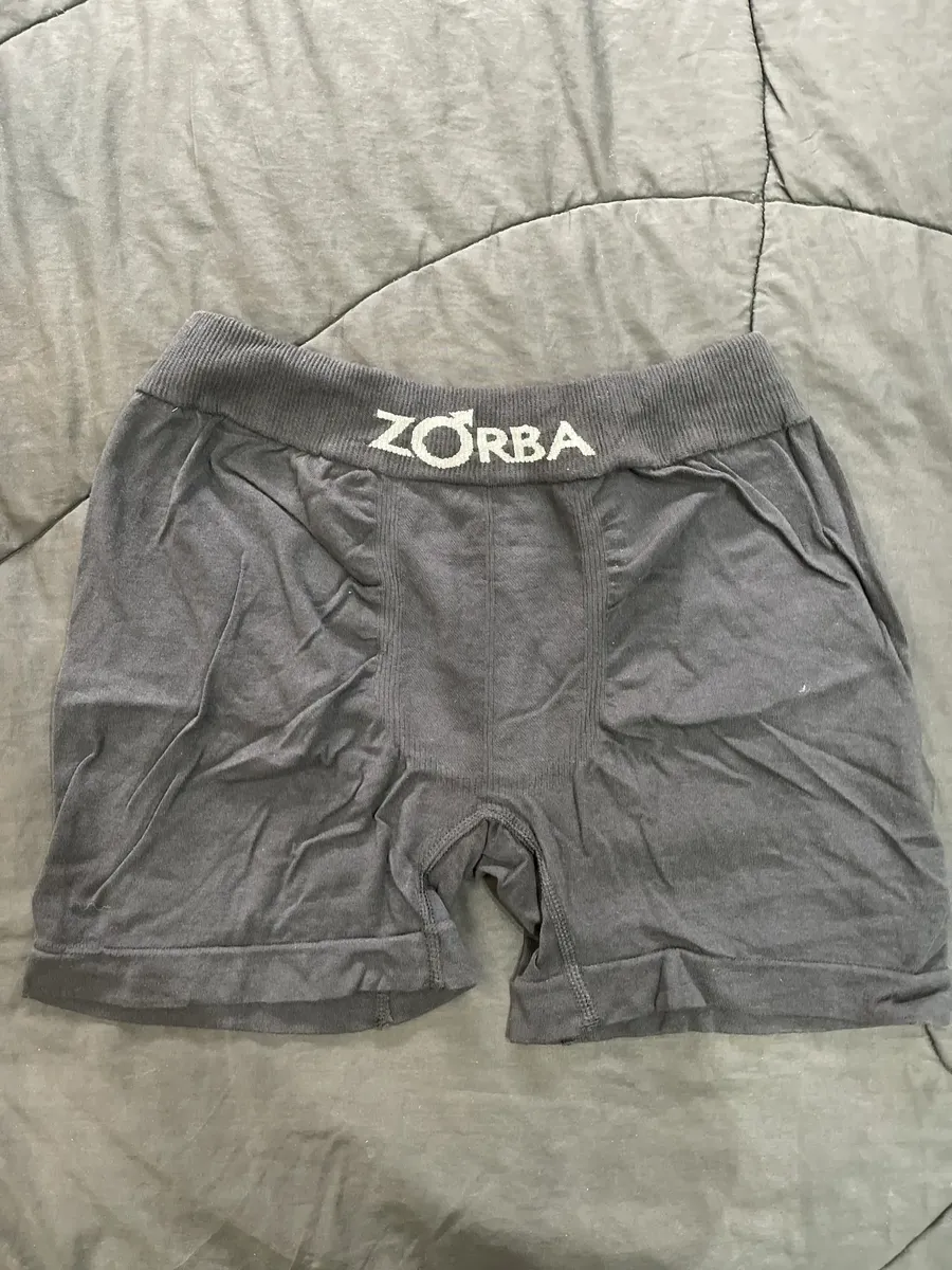 Foto de cliente mostrando cueca Zorba cinza aberta sobre cama